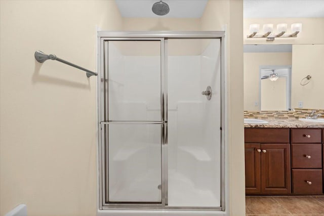 bathroom featuring backsplash, ceiling fan, vanity, and an enclosed shower