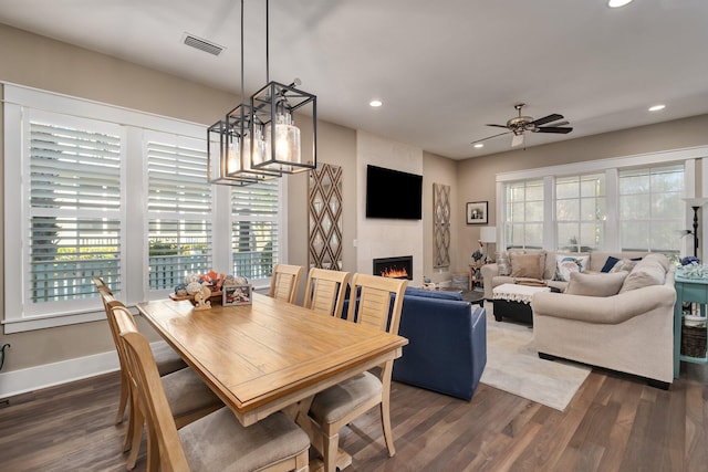 dining area featuring ceiling fan, a large fireplace, and dark hardwood / wood-style floors