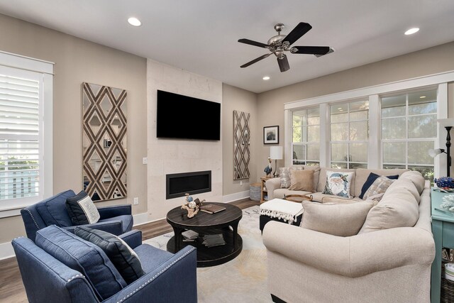 living room with a tile fireplace, hardwood / wood-style floors, and ceiling fan