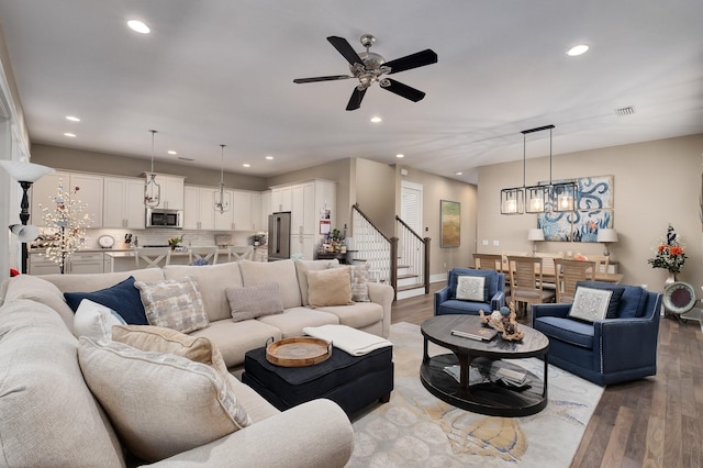 living room with ceiling fan with notable chandelier and light wood-type flooring