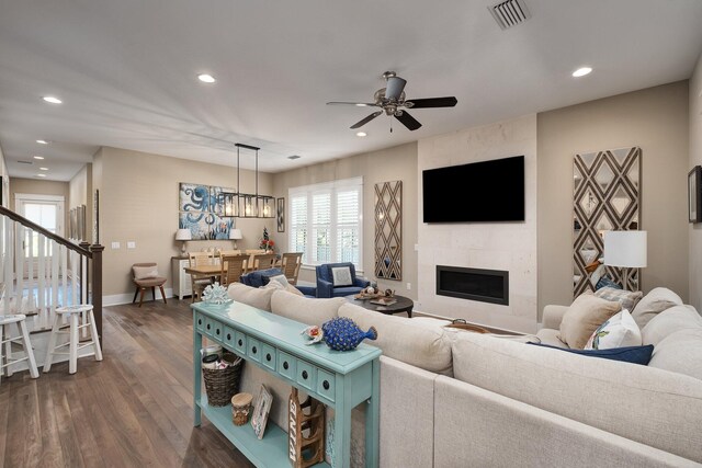 living room featuring a fireplace, ceiling fan with notable chandelier, and dark hardwood / wood-style floors