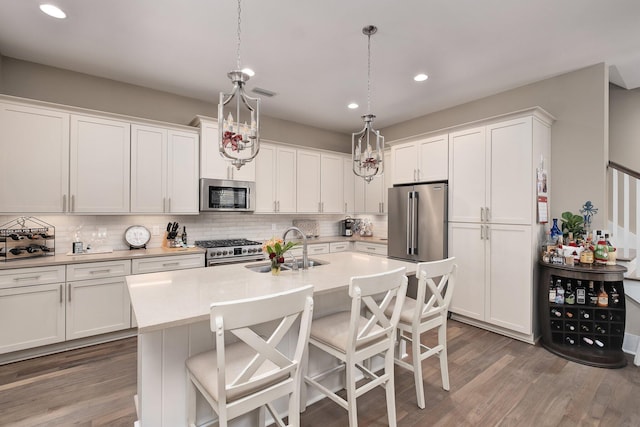 kitchen featuring pendant lighting, high end appliances, dark wood-type flooring, white cabinets, and sink