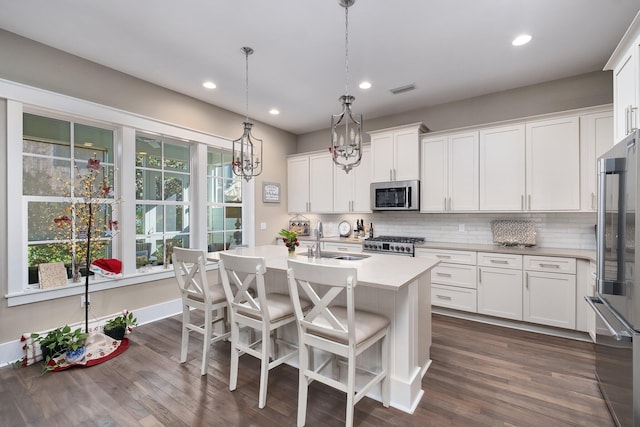 kitchen featuring dark wood-type flooring, white cabinets, stainless steel appliances, and decorative light fixtures