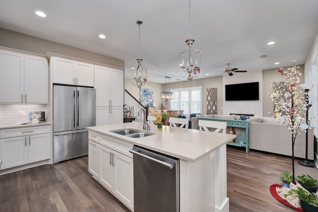 kitchen with ceiling fan, white cabinetry, stainless steel appliances, and an island with sink