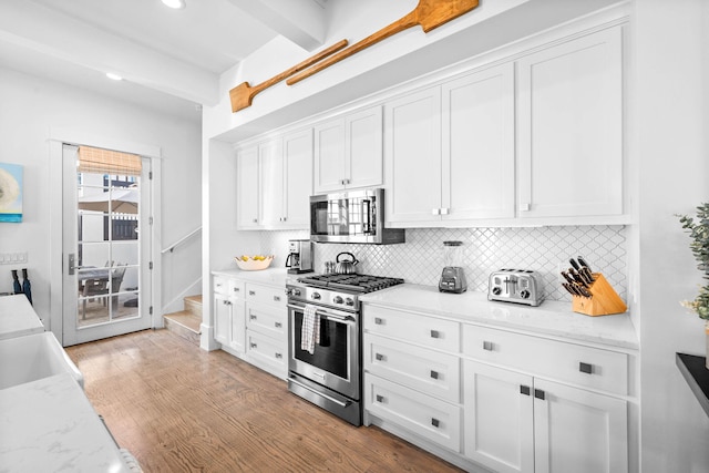 kitchen with beamed ceiling, light wood-type flooring, white cabinetry, and stainless steel appliances