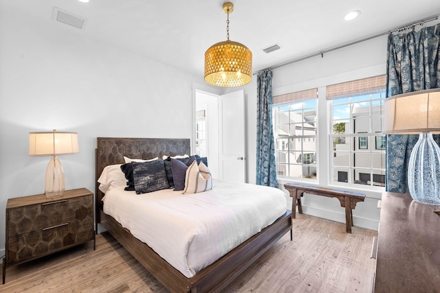 bedroom with wood-type flooring and an inviting chandelier