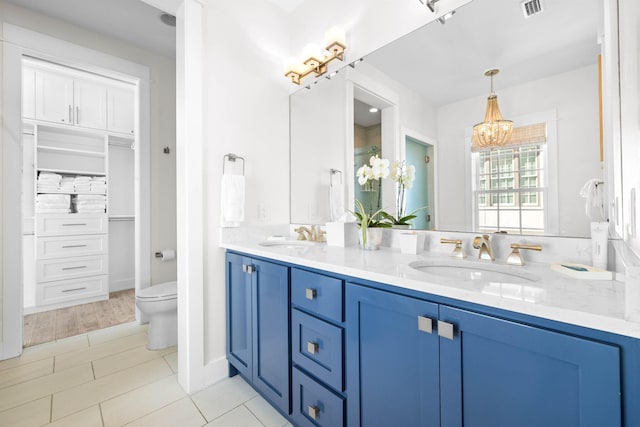 bathroom with tile patterned flooring, vanity, toilet, and a notable chandelier