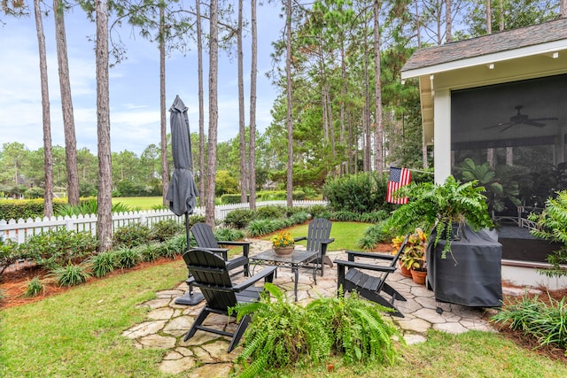 view of yard featuring a sunroom, ceiling fan, and a patio area