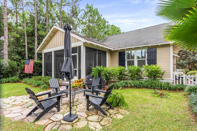 rear view of house with a sunroom, a yard, and a patio