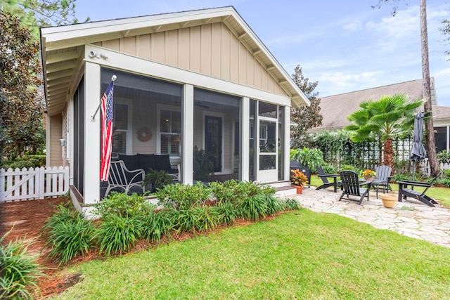 back of property with a sunroom, a yard, an outdoor fire pit, and a patio