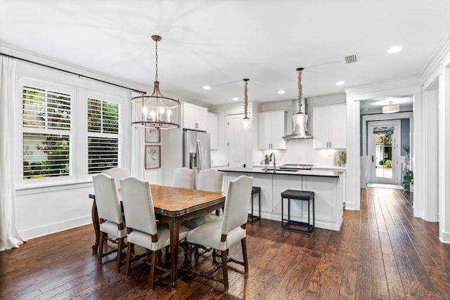 dining room with dark hardwood / wood-style flooring, ornamental molding, sink, and an inviting chandelier