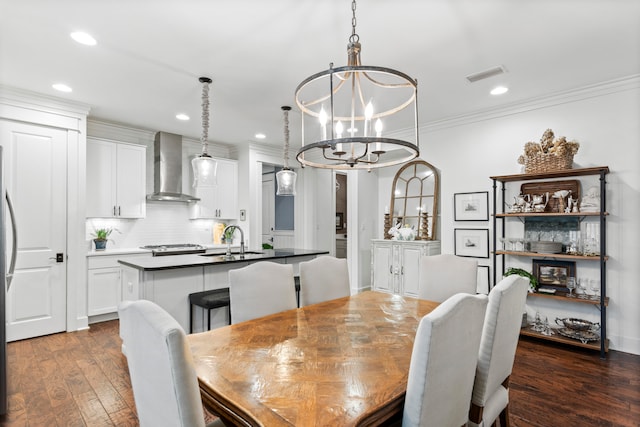 dining room with dark hardwood / wood-style flooring, ornamental molding, sink, and a chandelier