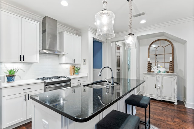 kitchen featuring white cabinets, wall chimney exhaust hood, stainless steel range with gas cooktop, and an island with sink