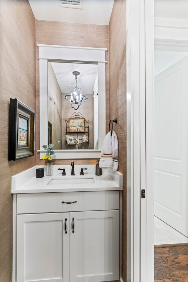 bathroom with hardwood / wood-style floors, vanity, and a chandelier