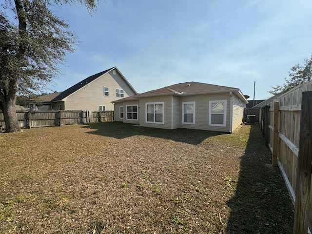 back of property with central AC unit and a lawn