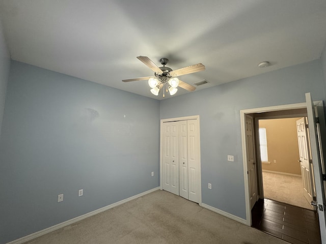 unfurnished bedroom with ceiling fan, a closet, and light carpet