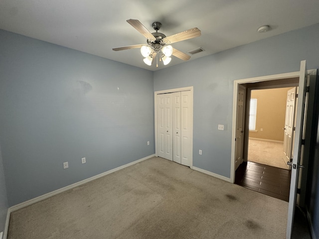 unfurnished bedroom featuring ceiling fan, light colored carpet, and a closet