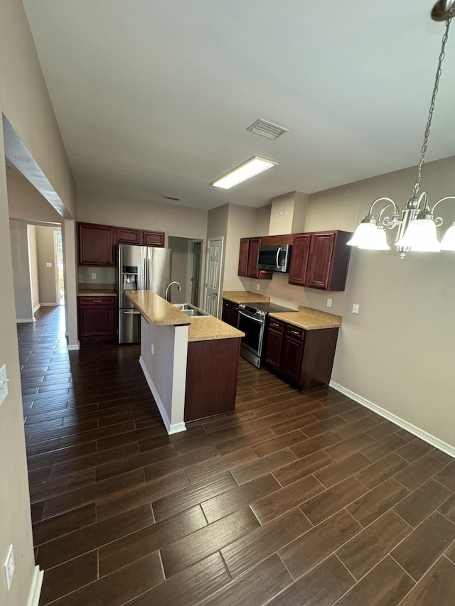 kitchen featuring pendant lighting, a center island with sink, sink, an inviting chandelier, and appliances with stainless steel finishes