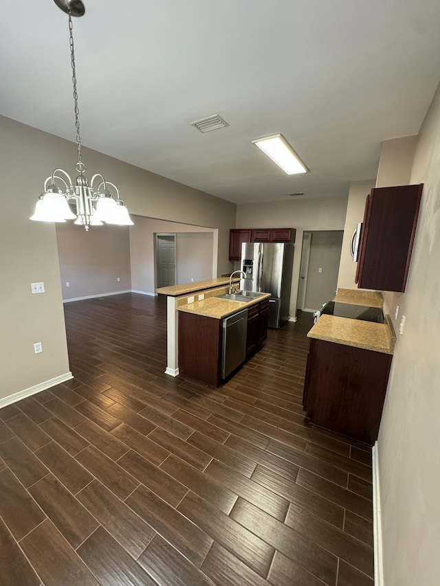 kitchen featuring a notable chandelier, pendant lighting, sink, appliances with stainless steel finishes, and an island with sink