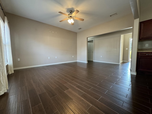 empty room with ceiling fan, plenty of natural light, and dark hardwood / wood-style flooring