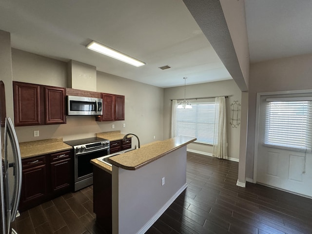 kitchen with decorative light fixtures, a wealth of natural light, stainless steel appliances, and a kitchen island with sink