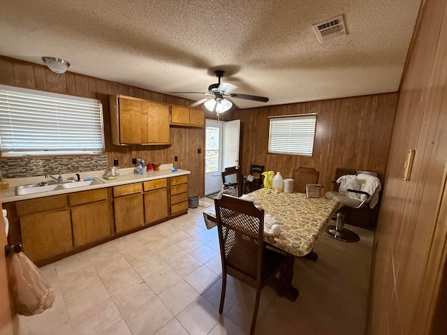 kitchen featuring decorative backsplash, wood walls, sink, and a textured ceiling