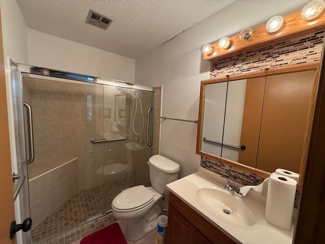 bathroom with vanity, toilet, a shower with shower door, and a textured ceiling