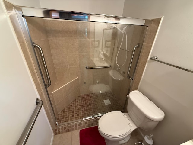 bathroom with toilet, a shower with door, and tile patterned flooring