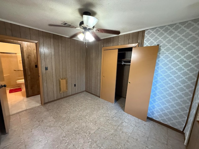 unfurnished bedroom featuring ceiling fan, a closet, a textured ceiling, and wooden walls