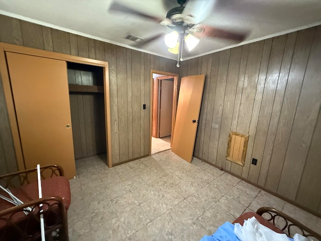 bedroom featuring wooden walls, a closet, ceiling fan, and crown molding