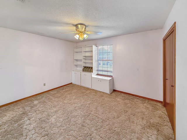 unfurnished bedroom featuring ceiling fan, light colored carpet, and a textured ceiling