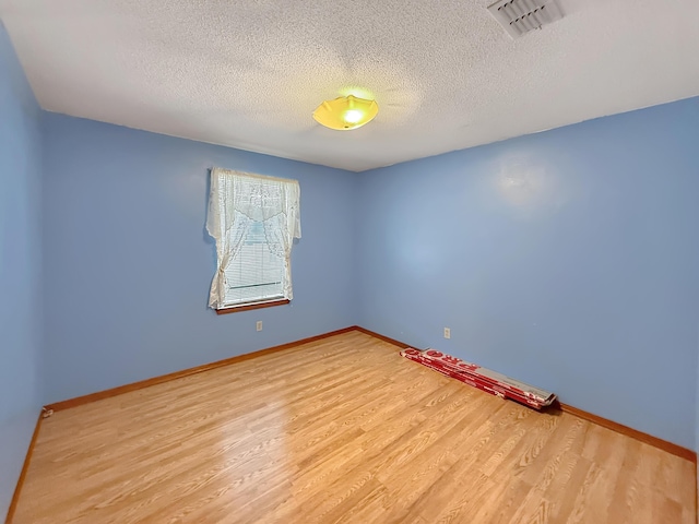 unfurnished room with light hardwood / wood-style flooring and a textured ceiling