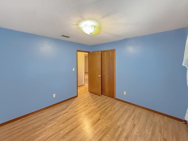 unfurnished bedroom with a closet, a textured ceiling, and light hardwood / wood-style flooring