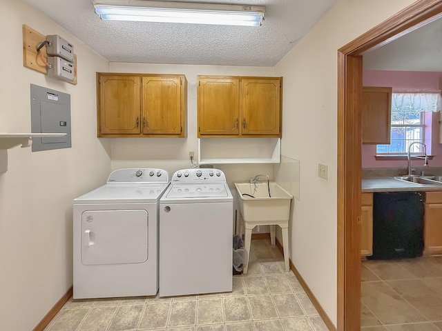 washroom with sink, electric panel, cabinets, independent washer and dryer, and a textured ceiling