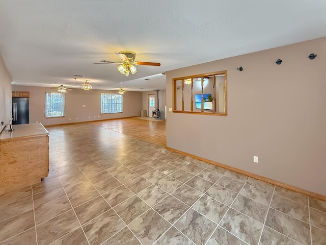 unfurnished living room featuring tile patterned flooring, ceiling fan, and a textured ceiling