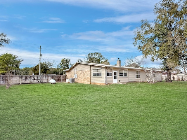 rear view of house with cooling unit and a yard