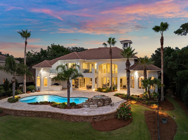 pool at dusk with a jacuzzi and a patio