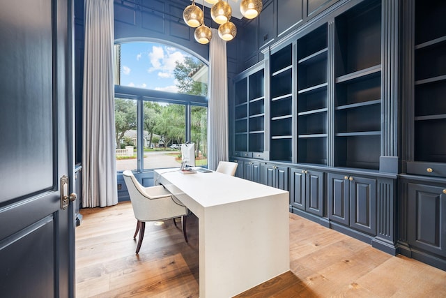 office area with built in shelves, hardwood / wood-style floors, and an inviting chandelier