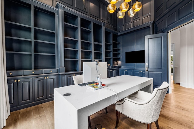 office featuring wood-type flooring, an inviting chandelier, and built in shelves