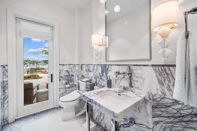 bathroom with toilet and tile walls