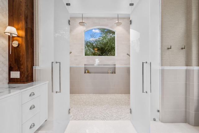 bathroom featuring vanity, tile walls, and walk in shower