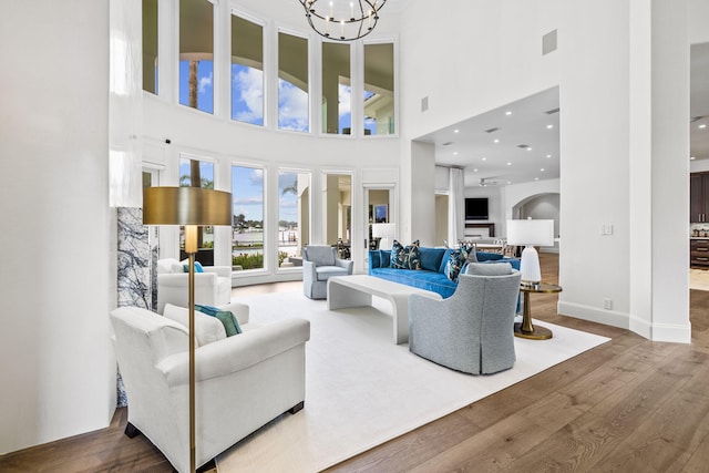 living room with hardwood / wood-style floors, a notable chandelier, and a towering ceiling