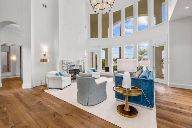 living room with a high end fireplace, a high ceiling, crown molding, and hardwood / wood-style floors