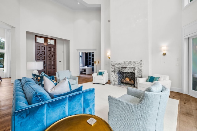 living room featuring a fireplace, hardwood / wood-style floors, and a towering ceiling