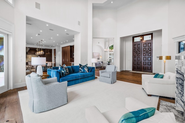 living room with hardwood / wood-style floors, a towering ceiling, and a chandelier