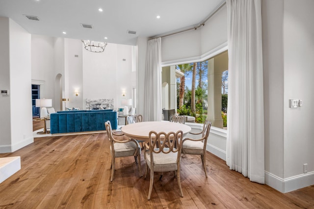 dining area featuring a towering ceiling, light hardwood / wood-style floors, and an inviting chandelier