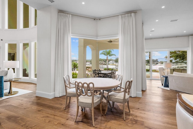 dining room with a high ceiling, light hardwood / wood-style flooring, and ceiling fan