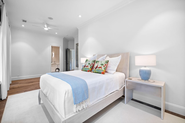 bedroom featuring light wood-type flooring, ensuite bathroom, and crown molding