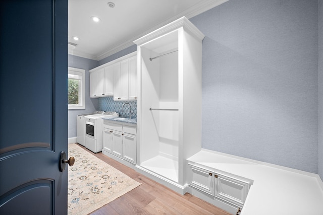 laundry room featuring sink, cabinets, light hardwood / wood-style flooring, washer and dryer, and ornamental molding