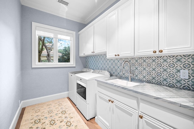 laundry room featuring cabinets, crown molding, sink, light hardwood / wood-style flooring, and independent washer and dryer